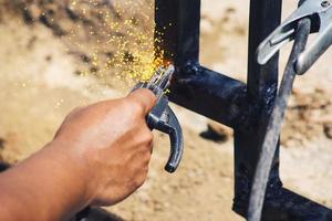 um trabalhador está soldando ferro sem usar luvas. trabalho de soldagem leve. foto