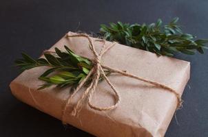 caixa de presente artesanal com nó natural com folhas verdes sobre fundo preto