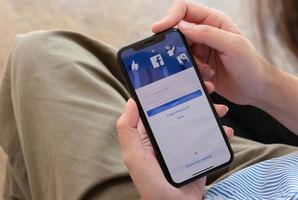 mulher segurando um iphone x com facebook de serviço de internet social na tela. foto