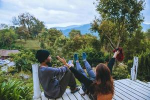 casal amante natural viajar na montanha, sentar-se relaxar lendo livros no meio da natureza na ponte de madeira branca. foto