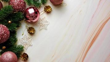 folhas de pinheiro verde, decorações de Natal rosa e bastões de doces em fundo de mármore macio, decorações de Natal em cor-de-rosa brilhante e extravagante. conceito de Natal simples e criativo. foto