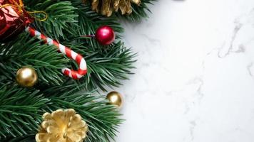 folhas de pinheiro verde, decorações de Natal vermelhas e bastões de doces em fundo de mármore branco, decorações de Natal em cor vermelha brilhante. conceito de Natal simples e criativo. foto