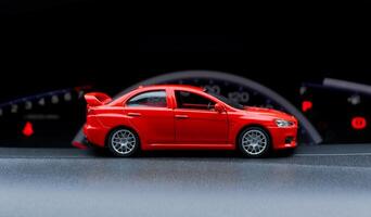 vermelho brinquedo carro dentro uma real carro com velocímetro fundo. depois de alguns Editar% s. foto
