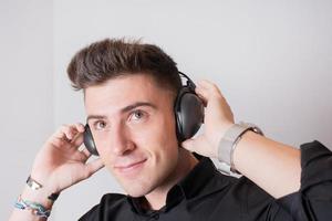 close-up de um jovem atraente de preto, ouvindo um podcast enquanto sorria. foto