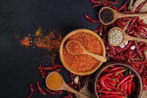 seco pimentões com Pimenta pó, pimenta, e vermelho páprica dentro uma de madeira tigela picante tempero saudável comida, topo Visão foto