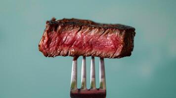 grelhado carne bife em uma garfo em uma verde fundo fechar-se foto