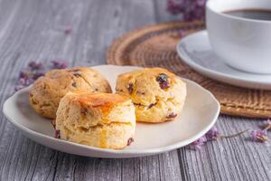 fechar-se do tradicional britânico scones e biscoitos em uma prato com uma xícara de chá e flor borrado fundo. espaço para texto foto