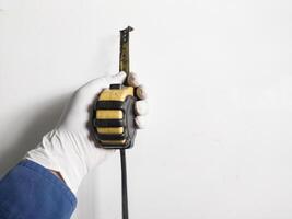 do homem mão com luvas detém uma aço medindo fita amarelo abnd Preto cor isolado em branco fundo. foto