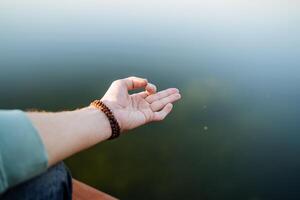 a mão mostra a elemento do ioga, a prática do meditação dentro silêncio, a dedos do a mão contra a fundo do a água, ioga em a mar dentro a verão, colocar a símbolo em a mão foto