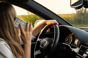 feliz jovem mulher Falando de Móvel telefone enquanto dirigindo carro. o negócio mulher falando telefone ligar dentro automóvel. inseguro arriscado dirigindo. conceito do multitarefa foto