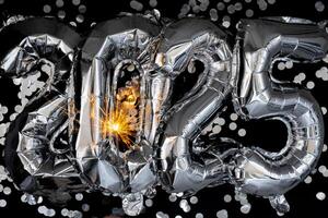feliz Novo ano 2025 metálico balões com confete e diamante fogo de artifício Bengala luzes em Sombrio Preto fundo. cumprimento cartão prata frustrar balões números Natal feriado conceito. celebração festa parabéns decoração foto