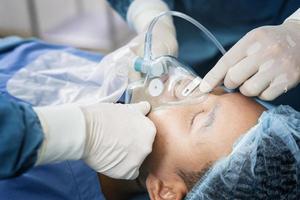 o cirurgião assistente colocou o paciente em uma máscara de ventilador de oxigênio em preparação para a cirurgia.