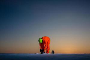 snowboarder no topo de uma pista de esqui ao fundo de um belo pôr do sol foto