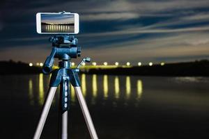 usando smartphone como uma câmera profissional no tripé para capturar paisagens noturnas foto