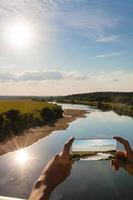 alguém usando o smartphone para tirar uma foto de uma paisagem de verão