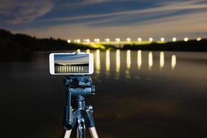 usando smartphone como uma câmera profissional no tripé para capturar paisagens noturnas foto