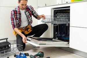 trabalhador reparação a lava-louças dentro a cozinha foto