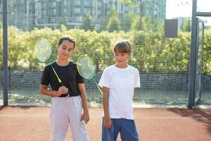 dois meninas com badminton raquetes em a futebol campo. foto