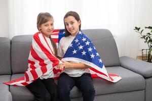 alegre adorável crianças em pé debaixo americano bandeira e olhando às Câmera foto