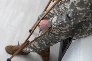 soldado dentro cáqui militares uniforme em muletas foto