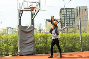 pai e Adolescência filha jogando basquetebol lado de fora às quadra foto