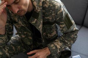 depressivo soldado com garrafa sentado dentro vivo sala. álcool vício. foto