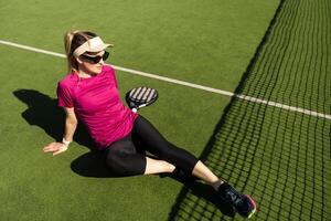 ativo jovem mulher tentando para batida a bola de padel raquete enquanto jogando tênis dentro a quadra foto