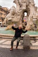 feliz meio envelhecido homem em período de férias levando uma selfie dentro frente do a fonte dentro praça Navona dentro Roma foto