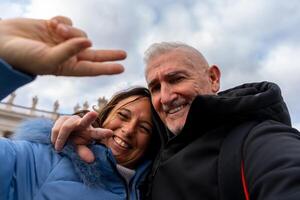 feliz meio envelhecido casal em período de férias levando uma selfie dentro frente do santo de Pedro basílica dentro Roma foto