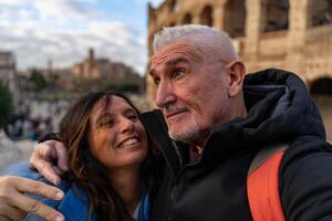 feliz meio envelhecido casal em período de férias levando uma selfie dentro frente do Coliseu anfiteatro dentro Roma foto