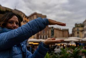 lindo meio envelhecido mulher viajando dentro Roma fofinho mostrando uma estátua dentro campo de Fiori foto