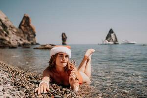 mulher viagem mar. feliz turista apreciar levando cenário em a de praia para recordações. mulher viajante dentro santa chapéu parece às Câmera em a mar baía, partilha viagem aventura viagem foto