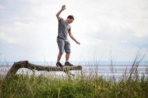 adulto jovem, equilibrando-se em uma árvore em férias foto