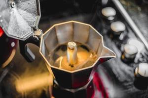 cafeteira italiana de alumínio preparando um café escuro e fresco no fogão foto