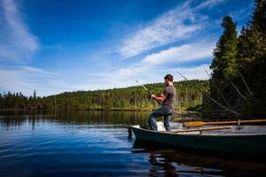 jovem adulto pescando truta em um lago calmo foto