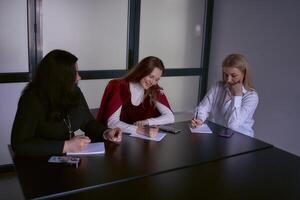 uma pequeno equipe do três mulheres trabalhos dentro a escritório foto