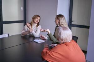 três mulheres, Incluindo uma pessoa com uma incapacidade, discutir a da empresa estratégia às uma encontro dentro a escritório foto