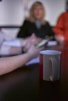 uma copo do café dentro a primeiro plano durante uma encontro dentro a escritório foto