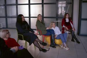 mulheres Assistir seus do colega discurso em estágio, sentado em cadeiras e feijão saco foto