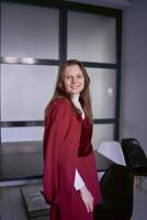 retrato do uma jovem mulher dentro uma vermelho escritório terno foto