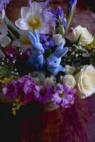 Páscoa floral arranjo com dois azul Páscoa coelhos dentro uma vime cesta foto