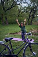 velho mulher práticas ioga dentro a manhã em a rio banco, veio a partir de casa de bicicleta foto