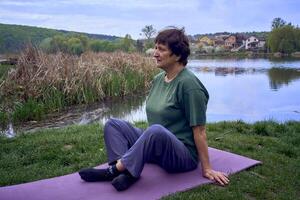 a velho mulher meditando dentro a manhã em a banco do a rio, veio a partir de casa de bicicleta foto