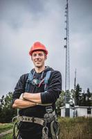 homem técnico de telecomunicações de uniforme com arnês foto