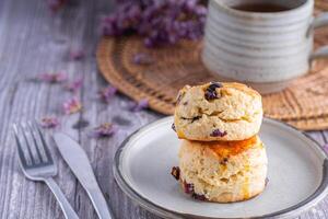 fechar-se do tradicional britânico scones em uma prato e uma chá quente copo com borrado fundo. espaço para texto foto