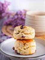 lado Visão do tradicional britânico scones em uma prato com uma chá copo e flor borrado fundo foto