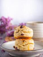 lado Visão do tradicional britânico scones em uma prato com uma xícara de chá e flor borrado fundo. espaço para texto foto