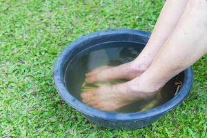 fechar-se do spa pé com ervas água para relaxamento tratamento. uma Senior mulher com tornozelo dor usa ervas tratamento para relaxar a músculos de encharcado caloroso água este é fervido a partir de ervas foto