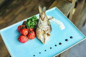 azul prato com peixe, tomates, e brócolis foto