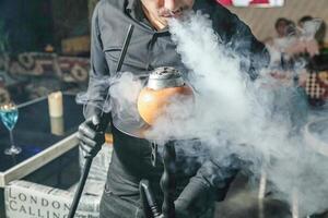 homem dentro Preto camisa segurando chaleira com fumaça foto